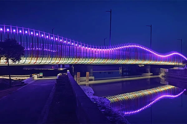 Close-up of linear lights tracing the curve of a bridge arch